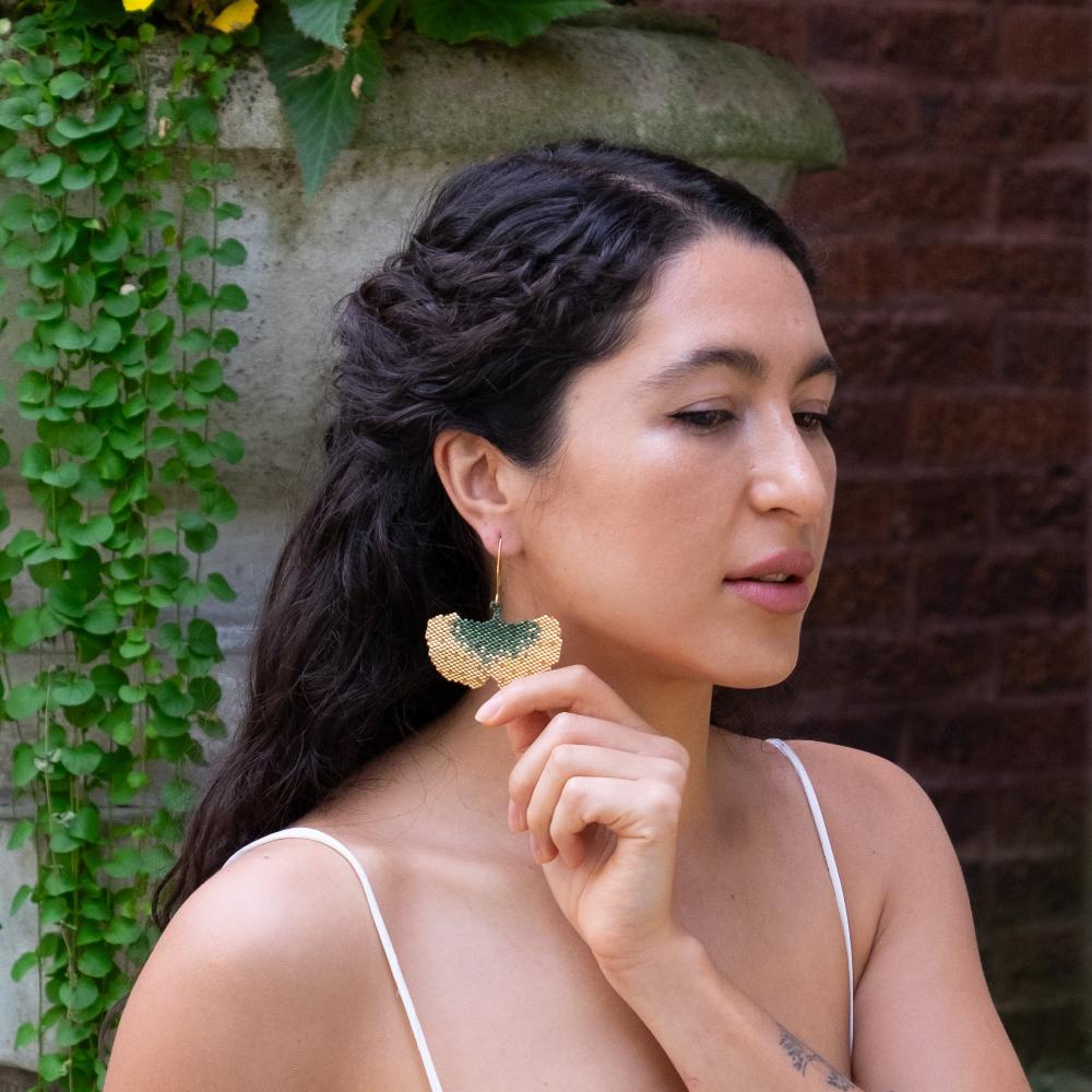 Colombian model wearing golden ginkgo earrings of glass beads