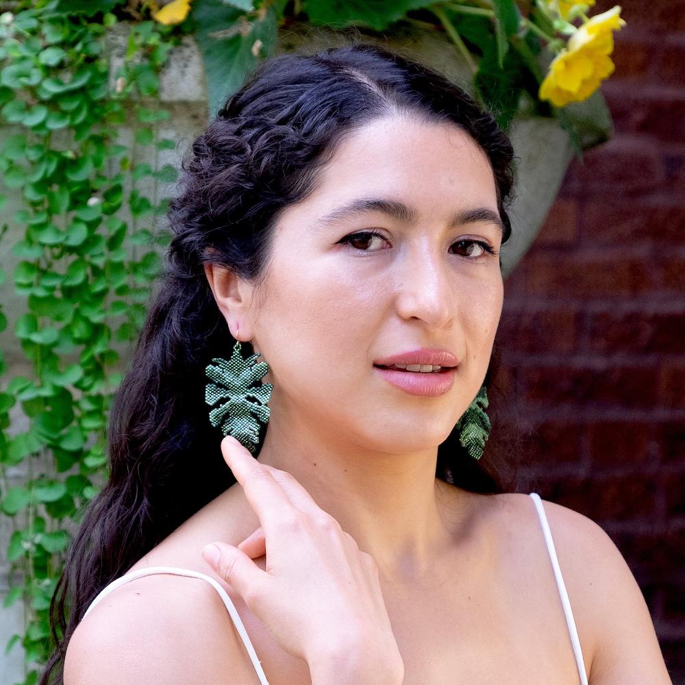 Colombian model wearing monstera leaf earrings made of glass beads