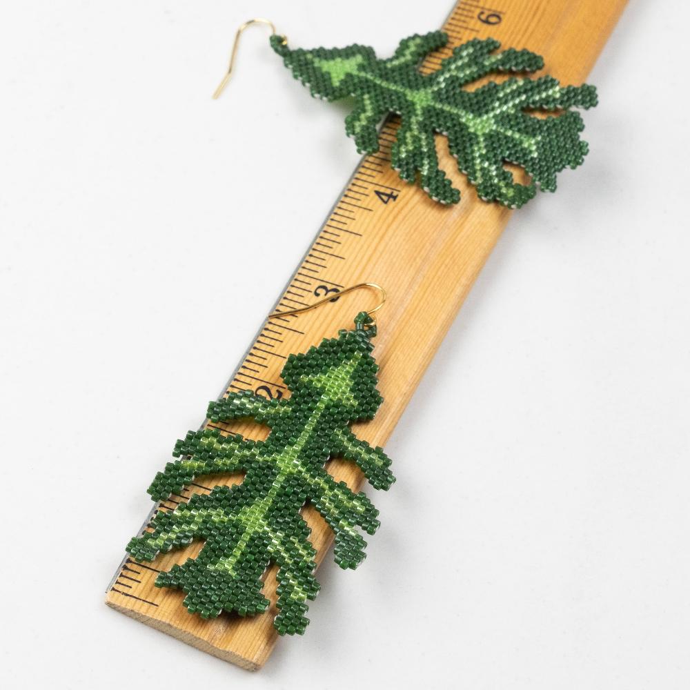 Oak leaf earrings made of glass beads with a wooden ruler in inches.